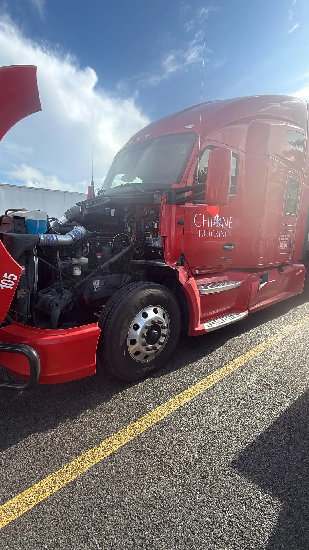 Red semi truck with hood open for repair